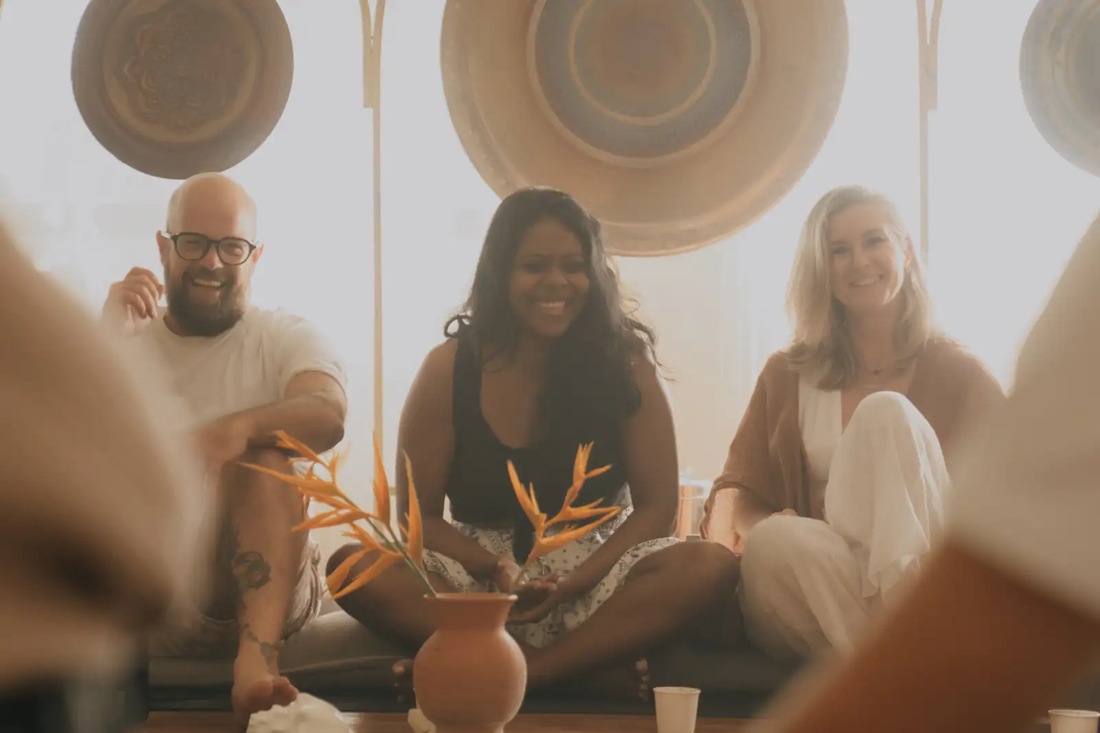 Three smiling participants sitting together in a circle during a breathwork training at Senses