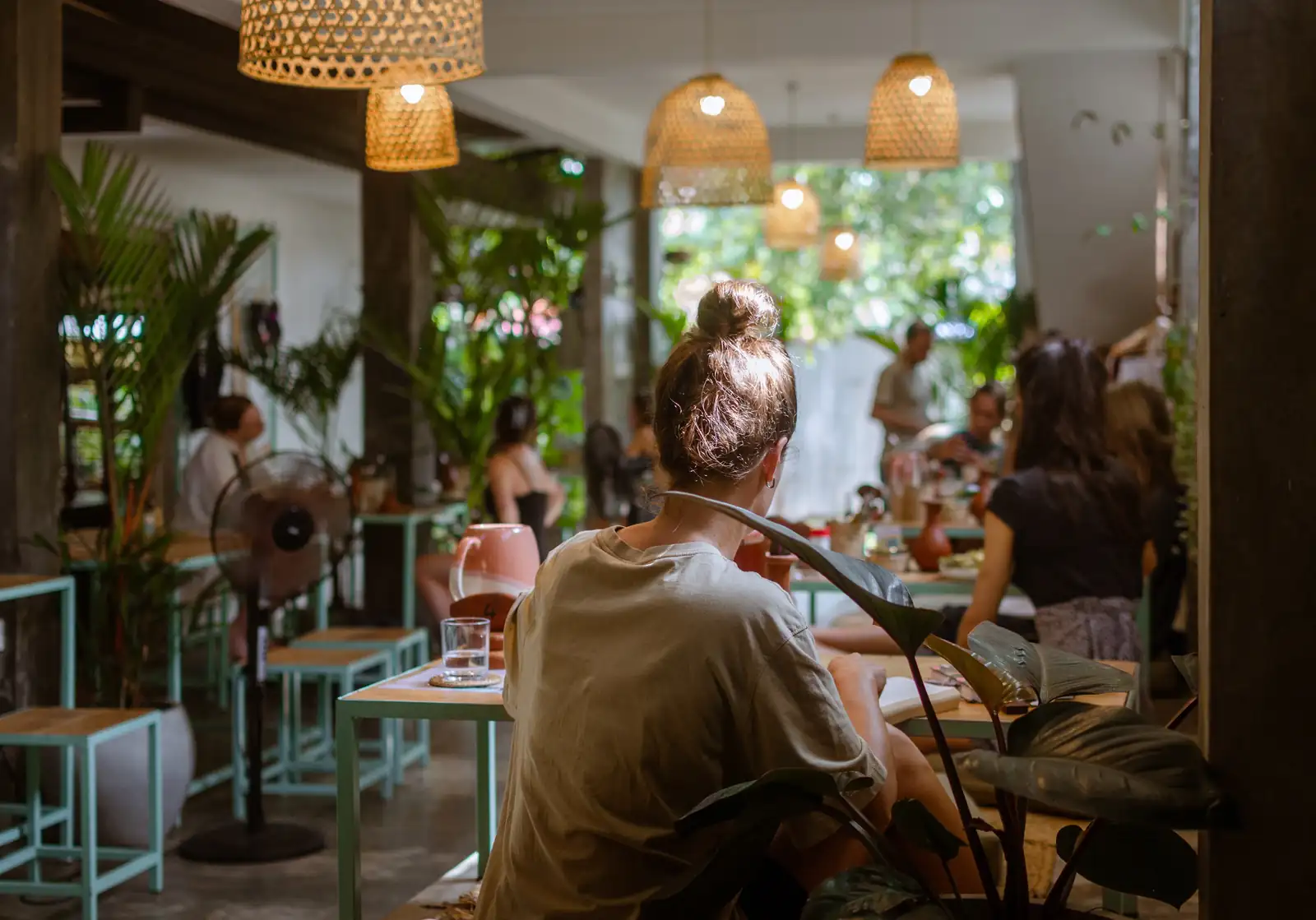 Guests at the communal mint green tables inside Flow Café, Weligama, with a smoothie on the table