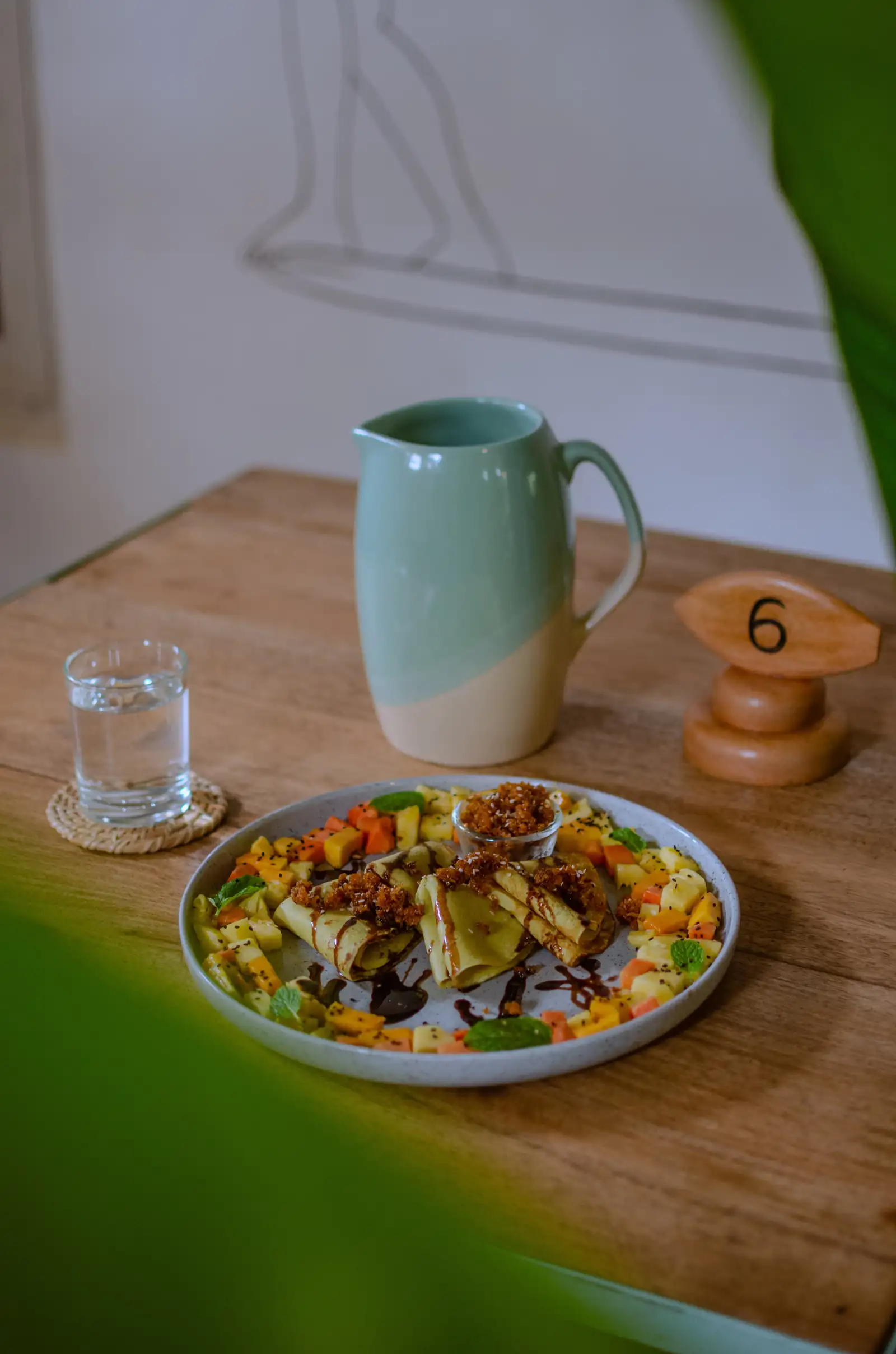 Crepes with fresh fruit and a jug of juice on a wooden table at Flow Café, Weligama