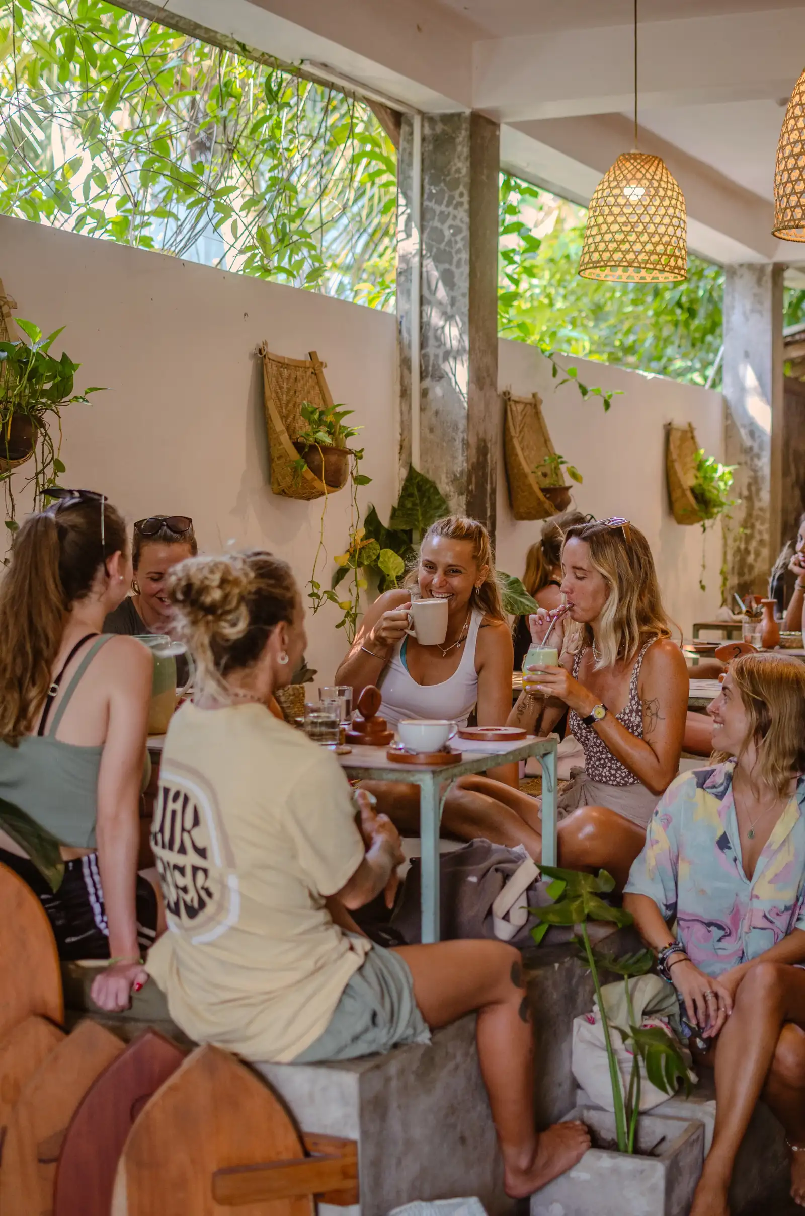 Friends laughing over coffee and matcha at a table at Flow Café, Weligama