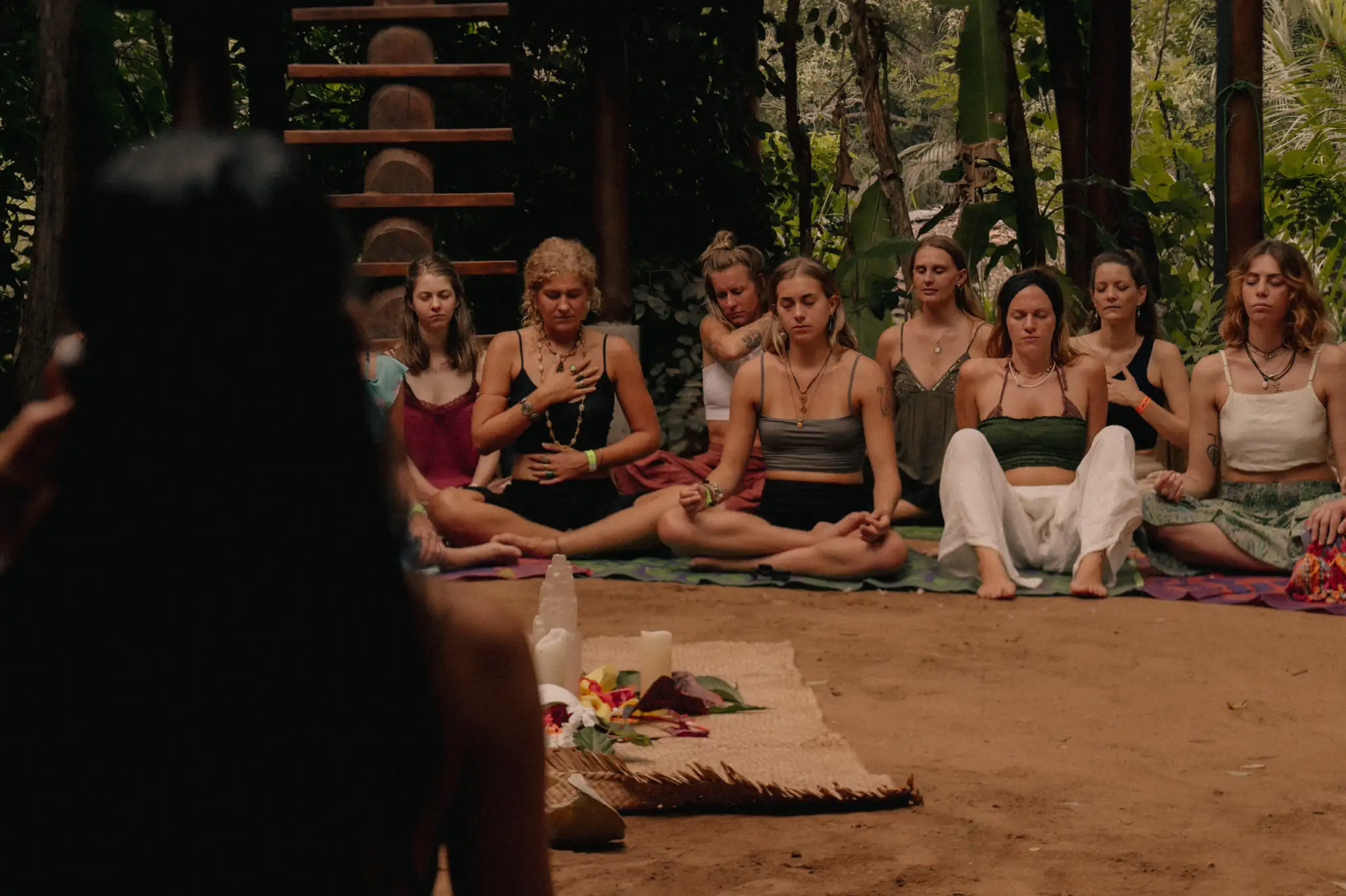 A facilitator holding space for a group sitting in a circle in meditation in the open-air garden at Senses in Midigama, Ahangama