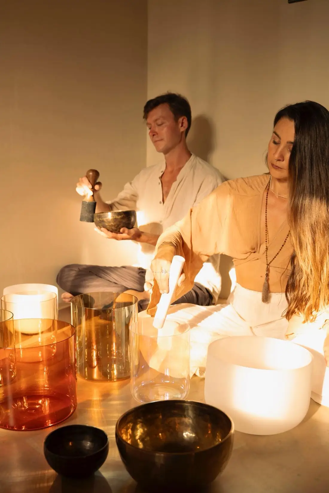 The Soulravel facilitators playing singing bowls in warm light